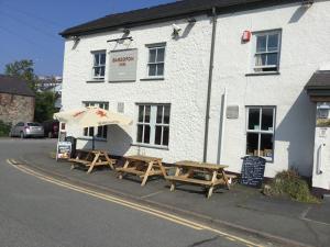 two wooden picnic tables in front of a building at Uwch Menai in Y Felinheli