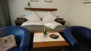 a bedroom with a bed and two blue chairs at Café Blaich - Hotel Garni in Höfen an der Enz