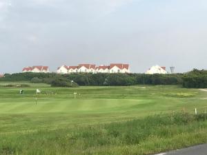 een golfbaan met een green en huizen op de achtergrond bij Appartement dans Résidence les Dunes du Golf in Wimereux