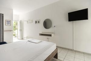 a white bedroom with a bed and a flat screen tv at Afkos Apartments in Polykhrono