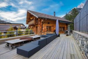 uma cabina de madeira com um deque com uma mesa e bancos em Chalet le Petou em Champéry