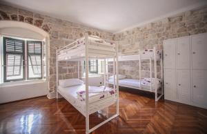 a room with two bunk beds and a brick wall at Hostel Angelina Old Town in Dubrovnik