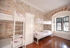 a room with two bunk beds and a brick wall at Hostel Angelina Old Town in Dubrovnik