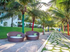 dois bancos sentados num parque com palmeiras em Marulhos Resort Porto de Galinhas (Muro Alto) em Porto de Galinhas