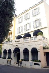 een groot wit gebouw met boogramen aan een straat bij Hotel De Monaco in Cap d'Ail