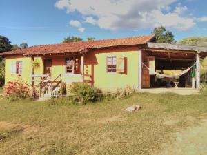 una pequeña casa amarilla con un perro delante de ella en Sítiio São Miguel projeto agroecológico en Caconde