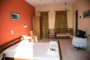 a bedroom with a bed and a living room with a tv at Almyros Studios & Apartments in Kounopetra