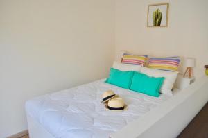a white bed with a hat sitting on it at Studio Liberté Plein Centre in Saint-Raphaël
