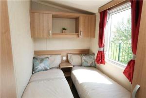 a small room with two beds and a window at Pine drive in Mablethorpe