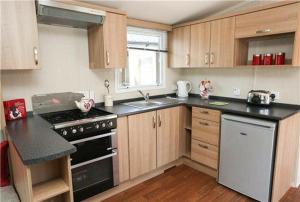 a kitchen with wooden cabinets and a black stove top oven at Pine drive in Mablethorpe
