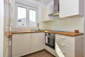 Biała kuchnia z białymi szafkami i oknem w obiekcie Makarska SUN Suite w Makarskiej