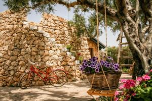 a red bike parked next to a stone building with flowers at B&B Corallo in Capilungo