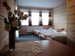 ザコパネにあるWilla Perełkaのベッド2台、テーブルに花瓶が飾られています。
