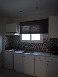 a kitchen with white cabinets and a window with a sink at Modern sea view appartment in Artemida