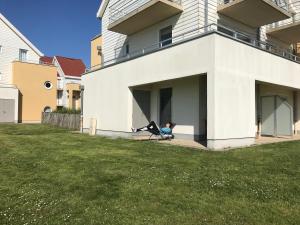 een persoon die op een stoel in het raam van een huis zit bij Appartement dans Résidence les Dunes du Golf in Wimereux