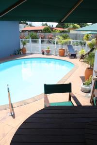 una gran piscina con 2 sillas y una mesa en Avenue Heights Motel, en Whangarei