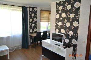 a living room with a desk with a tv and a wall with flowers at Melīna in Rēzekne