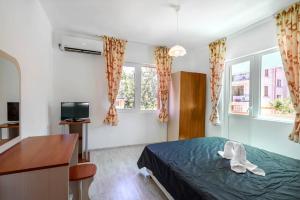 1 Schlafzimmer mit einem Bett, einem Schreibtisch und 2 Fenstern in der Unterkunft Guest House Galema in Obsor