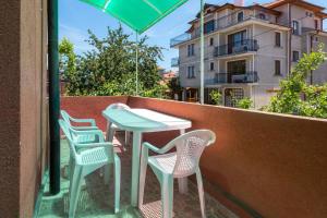 een tafel en stoelen op een balkon met een parasol bij Guest House Galema in Obzor