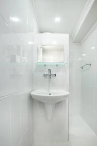 La salle de bains blanche est pourvue d'un lavabo et d'une douche. dans l'établissement Guest House Galema, à Obzor