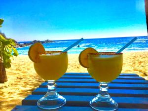 two glasses of juice on a table on the beach at Bungalow frente a la playa estrene alberca nueva con increíble vista infinita al mar, 8 hermosas playas cercanas, terraza con cama de playa, espectacular vista al inmenso océano pacífico, 2 kayack disponibles, nómadas digitales Starlink WiFi 224 mbps in Puerto Ángel