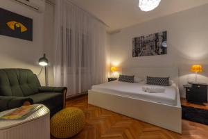 a bedroom with a bed and a couch and a chair at Apartman Karmen in Trogir