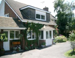 uma casa de tijolos com flores ao lado em Holly House B&B em Sittingbourne