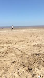 a beach with two people walking on the sand at Pine drive in Mablethorpe