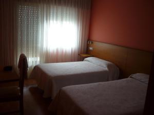 a hotel room with two beds and a window at Pensión Risco in Vimianzo