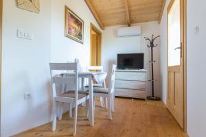 una sala da pranzo con tavolo, sedie e TV di Eco Holiday Home Lavanda a Funtana