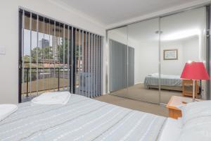 a bedroom with a bed and a large window at Parkside Apartments Parramatta in Sydney