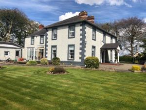 uma grande casa branca com um relvado em frente em Old Parochial House em Dundalk