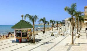 a beach with palm trees and a kiosk on the beach at Mediterranean View in Marina di Ragusa