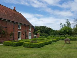 einen Garten vor einem Haus mit Büschen in der Unterkunft Dairy Cottage Luxury B&B in Attleborough