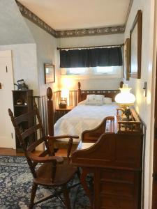 Old Iron Inn Bed and Breakfast في Caribou: غرفة نوم بسرير ومكتب وكرسي