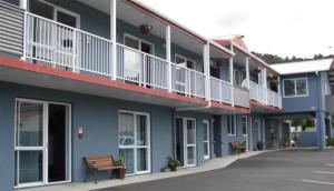 ein blaues Gebäude mit Balkonen und einer Bank davor in der Unterkunft Avenue Heights Motel in Whangarei