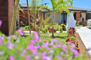 a garden with pink flowers in front of a house at Eden Appartel in Koné