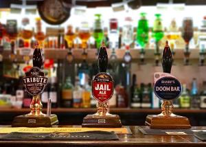 a bar with three different types of bottles of alcohol at Jolly Sailor Inn - THE OLDEST PUB IN LOOE - Family run and full of charm and character in Looe