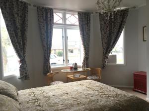 a bedroom with a bed and a table and windows at Fossil Coast B&B in Hawera