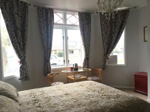 1 dormitorio con cama, mesa y ventanas en Fossil Coast B&B en Hawera