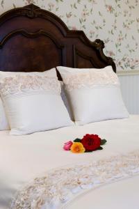 a bed with white pillows and two flowers on it at The Residence at Barossa Chateau in Lyndoch