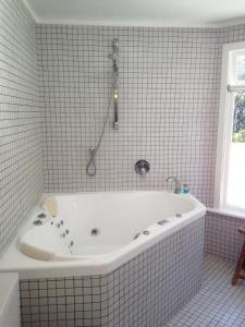 a white bath tub in a tiled bathroom at Ohiwa Seascape Studios in Opotiki
