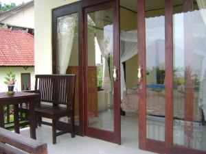 Habitación con puertas correderas de cristal y silla de madera. en Sinar Bali 2, en Amed
