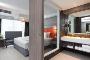 a hotel room with a bed and a tub and a sink at Grand 5 Hotel & Plaza Sukhumvit Bangkok in Bangkok