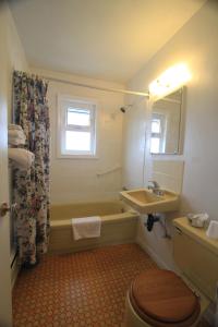 a bathroom with a tub and a sink and a toilet at Sunset Motel in Port Alberni