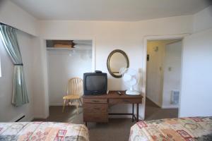 a bedroom with a television on a dresser with a mirror at Sunset Motel in Port Alberni