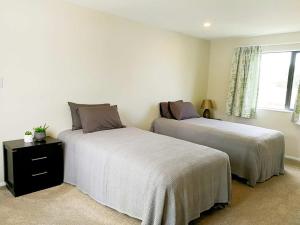 1 dormitorio con 2 camas y ventana en Stunning Stay In Glen Eden Auckland en Auckland