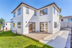 a large white house with a wooden deck at Stunning Stay In Glen Eden Auckland in Auckland