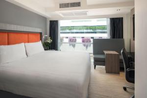 a hotel room with a bed and a desk and a window at Grand 5 Hotel & Plaza Sukhumvit Bangkok in Bangkok