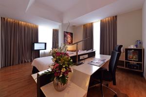una habitación de hotel con una cama y una mesa con flores en FOX Hotel Pekanbaru, en Pekanbaru